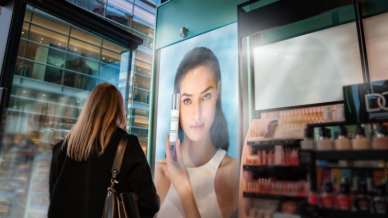 A shopper views digital retail media displays inside a Douglas beauty store powered by Broadsign’s in-store advertising platform (Image: Douglas)