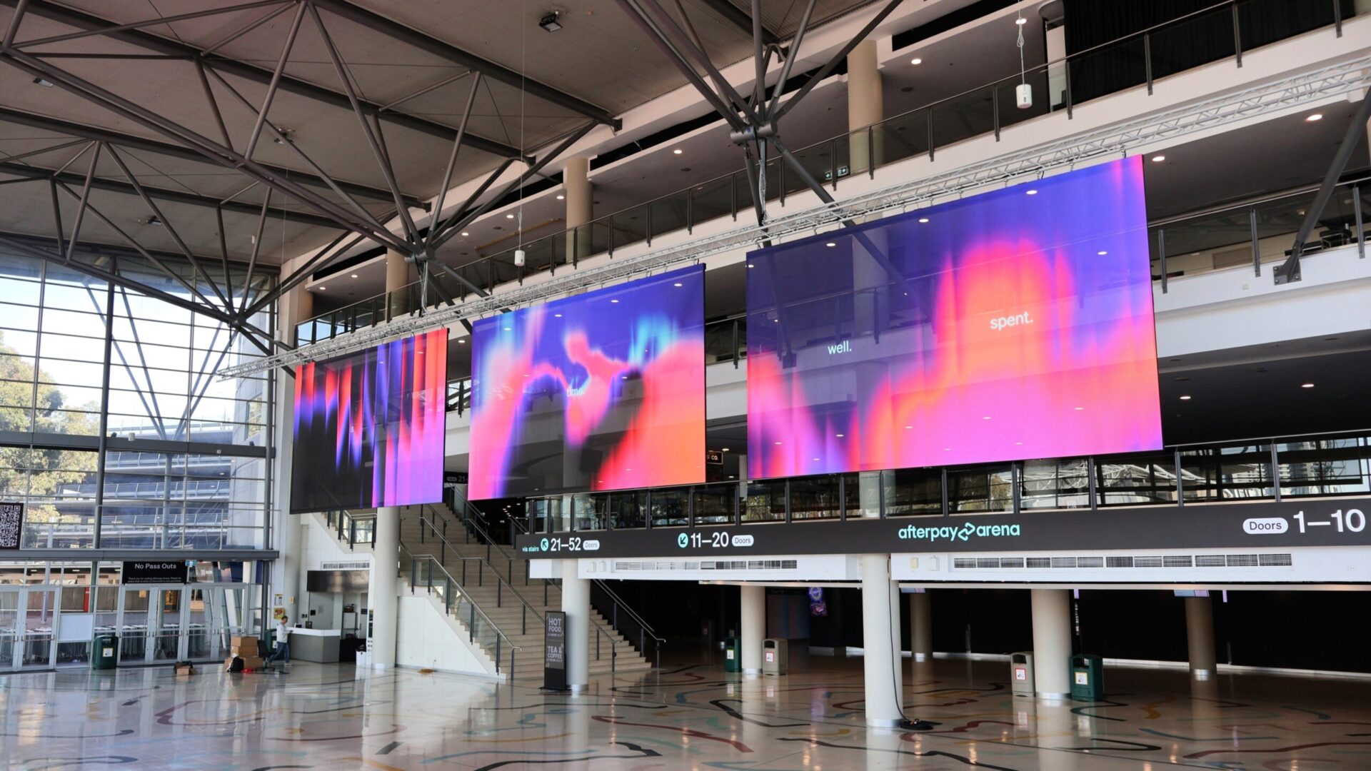 Three transparent LED displays suspended above Afterpay Arena's Grand Foyer serve as the centerpiece of the venue's digital signage transformation (Image: Outsource Resource)