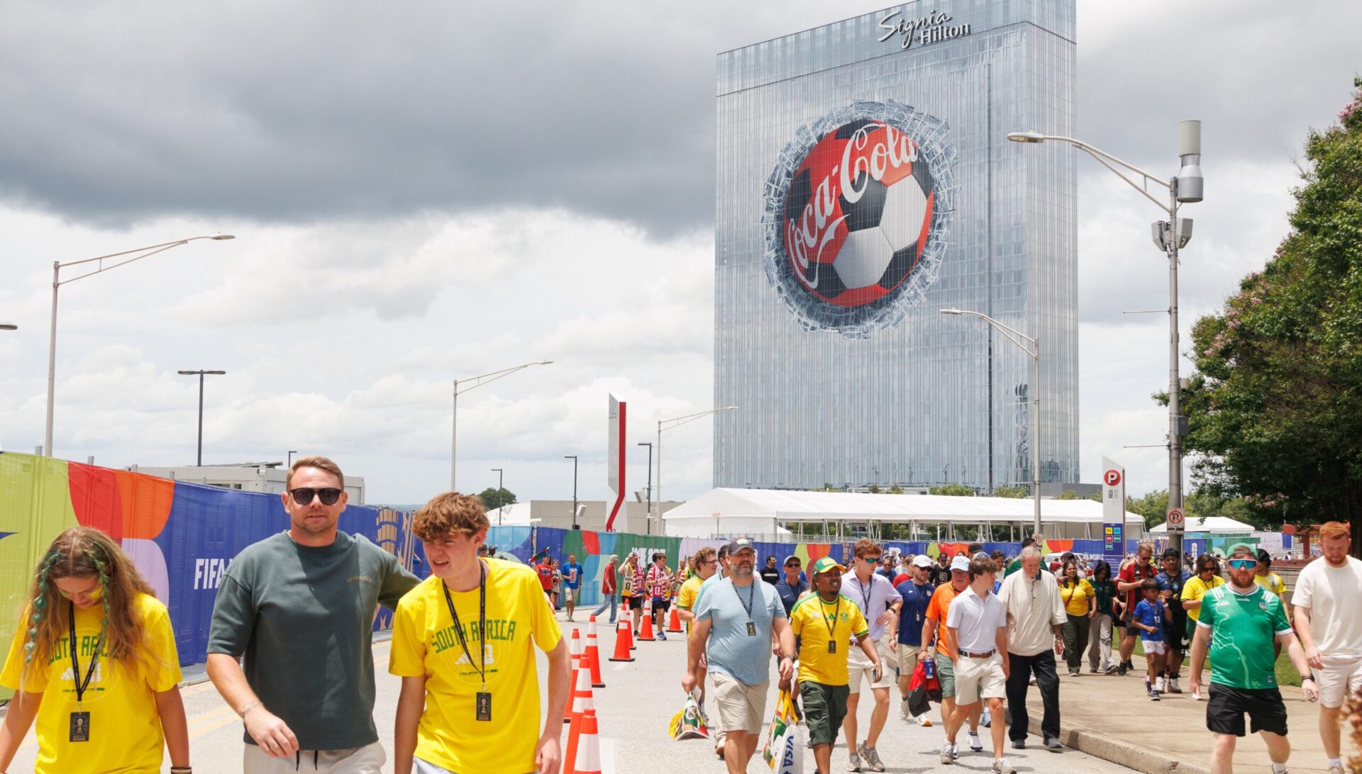 Branding Opportunities: World Cup Puts OoH in Spotlight Across US Host Cities - World Cup fans pass the Signia by Hilton Atlanta, where a Coca-Cola building wrap featured a giant soccer ball appearing to smash through the hotel’s windows. (Image: Outront Media) World Cup fans pass the Signia by Hilton Atlanta, where a Coca-Cola building wrap featured a giant soccer ball appearing to smash through the hotel’s windows. (Image: Outront Media)